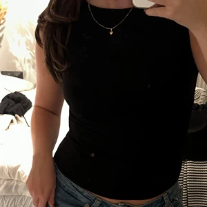 Svart topp med öppen rygg - Svart topp från BikBok med snygg öppen rygg och knyt i nacken. Toppen är figurnära och har en stilren, enkel design. Tillverkad i mjukt och stretchigt material för en bekväm känsla. Storlek S, använd 1 gång🩷