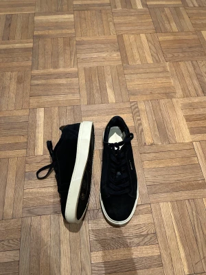 Svarta sneakers från GANT, strl 38  - Svarta sneakers från GANT med snygga gulddetaljer och logga på sidan och hälen. Ovandel i mocka och textil, vit platt sula och svarta snören. Baksidan har en glansig detalj som ger extra stilpoäng. Perfekt för dig som gillar klassisk och clean look. pris kan diskuteras