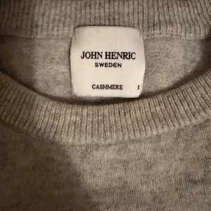 Grå cashmere-tröja John Henric - Mjuk och stilren grå tröja från John Henric i lyxig cashmere. Rund hals och långa ärmar med ribbade muddar vid ärmslut och nederkant. Perfekt för dig som gillar enkel och clean look med premiumkänsla.