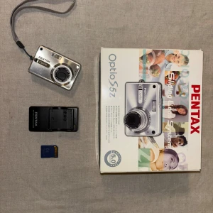 Pentax Optio S5z - Pentax Optio S5z digitalkamera i originalkartong med laddare och minneskort. Kompakt design, 5 megapixel, 3x optisk zoom. Kameran och tillbehör är i fint skock.