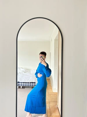 Blå långklänning från Gestuz - Säljer en snygg blå långklänning från Gestuz med rund hals, långa ärmar och coola knappdetaljer vid ärmsluten.Klänningen är gjord av återvunnen polyester och har en dragkedja i ryggen. Perfekt för dig som gillar stilrena och moderna plagg.                      Passform: Classic / Regular 36 men liten i rumpan (obs!)   Baklängd: 128 cm  Framlängd: 130 cm  🧵 Material:  Yttermaterial: 96% återvunnen polyester, 4% elastan  Foder: 100% viskos