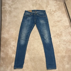 Blå dondup jeans med slitningar - Snygga blå Dondup jeans i slim fit med klassisk femficksdesign och diskreta slitningar framtill. Jeansen har normal midja och raka ben med smal passform. Materialet är mjukt jeans med stretch för extra komfort. Perfekt för dig som gillar stilrena och moderna jeans. Pris är alltid diskuterbart😁