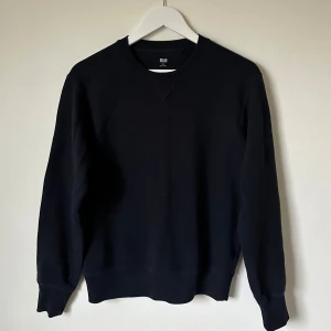 Mörkblå sweatshirt från Uniqlo XS - En stilren mörkblå sweatshirt från Uniqlo i storlek XS. Tröjan har rund hals, långa ärmar och är tillverkad i mjuk bomull med inslag av polyester. Perfekt för en chill och enkel look, passar dig som gillar basic och minimalistisk stil. 5J16