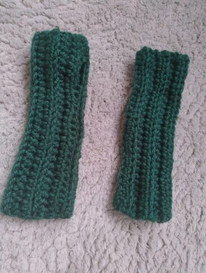 Mörkgröna virkade handledsvärmare - Säljer ett par mörkgröna virkade handledsvärmare som jag gjort själv. De är virkade i ett tjockt  garn och har en enkel, rak form som täcker handleden och en bit upp på underarmen. Perfekt för dig som vill ha värme men ändå kunna använda fingrarna fritt. 