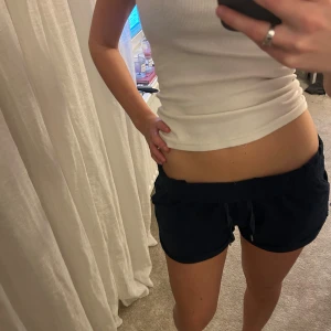 Mörkblå shorts med snörning - Säljer ett par mörkblå shorts med snörning i midjan och fickor på sidorna. De har en låg midja och är tillverkade i ett mjukt och bekvämt material, perfekta för sommardagar eller chill hemma. Klassisk och enkel design som är lätt att matcha.