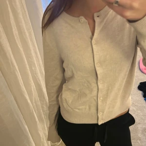 Beige kofta med knappar - Snygg beige kofta med rund hals och knäppning framtill. Tröjan har långa ärmar och ribbade muddar vid ärmslut och nederkant. Perfekt att slänga över en topp för en chill look. Mjuk och tunn, passar bra till både jeans och mjukisbyxor.