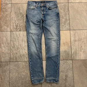 Nudie Jeans - Snygga blå jeans från Nudie Jeans med klassisk femficksdesign och orangea sömmar. Modellen är Steady Eddie II och har en rak passform. Jeansen är använda men är fortfarande i bra skick. Nypris är 1600kr. Hör av dig vid funderingar!