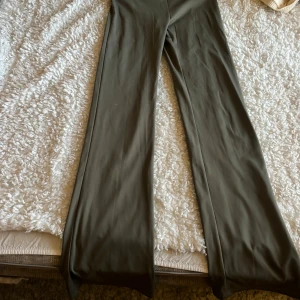 Olivgröna yoga pants  - Snygga olivgröna leggings med hög midja och ett stilrent, minimalistiskt tryck på linningen. Modellen har ett wide snitt med raka, vida ben och är tillverkad i ett mjukt och stretchigt syntetmaterial som sitter skönt hela dagen.