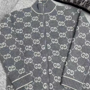 Gucci cardigan  - Tja, jag Säljer en grå kofta från Gucci med ikoniskt GG-mönster i vitt över hela plagget. Koftan har ribbad krage, muddar och nederkant samt dragkedja framtill. Materialet är stickad ull som känns lyxigt och mjukt. Perfekt för dig som vill ha en statement piece med designer-vibe. Fick den i present av farsan