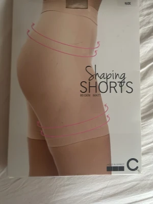 Beige shaping shorts från Cubus - Säljer ett par beige shaping shorts från Cubus i storlek XL. De är högmidjade och har en matt finish med platta sömmar för extra komfort. Materialet är 84% polyamid och 16% elastan med bomullsfodrad gren. Perfekta för att forma mage, höfter och lår.