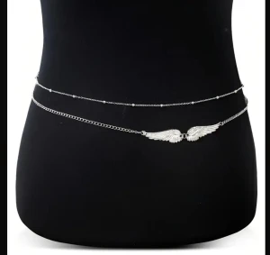 Silverfärgad midjekedja med vingar - Snygg midjekedja i silverfärgad metall med två tunna kedjor och en detalj med änglavingar framtill. Perfekt accessoar för stranden eller festivalen, ger en cool och unik touch till din outfit. Se mått på tredje bilden! Jag säljer den i silver!