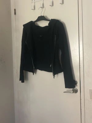 Svart stickad hoodie från Gina Tricot - Svart stickad hoodie från Gina Tricot i storlek L. Tröjan har huva, långa ärmar och dragkedja framtill. Ribbad struktur och loose passform ger en chill vibe. Perfekt för höst och vinter när du vill vara både bekväm och snygg. Pris kan diskuteras och tvätt ingår innan leverans. Du måste trycka in knappen lite hårdare när du knäpper den