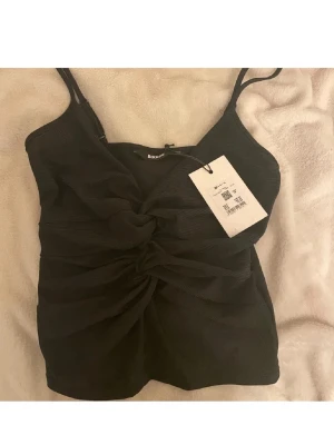 Svart glittrig topp  - Snygg svart glittrig linnetopp från Bikbok i storlek XS. Helt oanvänd med lapp på. perfekt till nyår tex 