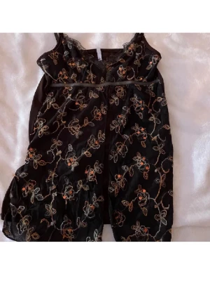 Svart blommig linnetopp med spets - Supersöt svart linnetopp från amisu vintage  med tunna axelband och spetsdetaljer vid urringningen. Storlek S 