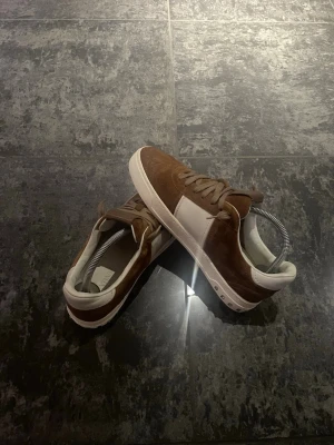 Valentino Flycrew Sneakers Brun Mocka | Strl 40 | 9/10 | Äkta - Exklusiva Valentino Flycrew sneakers i brun mocka, storlek 40. Skick 9/10 – nästan som nya. Endast lätt använda. Alla nitar är fortfarande kvar. Mockan i mycket fint skick  Minimal fläck längst ner på vita sulan, syns knappt. Bekväma & stilrena – passar både vardag & fest  📦 Skickas snabbt 💬 Pris kan diskuteras – bud välkomna