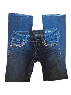 Miss Me blå bootcut jeans - Snygga blå jeans från Miss Me med bootcut passform och coola kedjedetaljer samt nitar på fickorna. Jeansen har kontrastsömmar och dekorativa bakfickor med mönstrad design. Materialet är klassisk jeans i bomull med stretch w26 