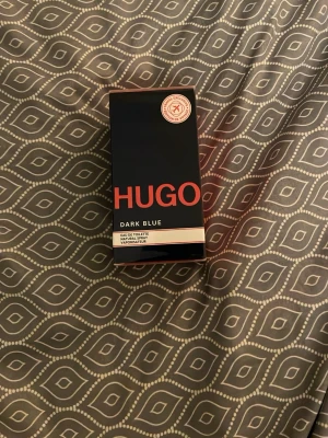 Hugo Dark Blue Eau de Toilette - Hugo Dark Blue Eau de Toilette är en modern parfym med stilren förpackning. Perfekt för dig som vill sticka ut med en klassisk och ungdomlig vibe. Volym och ingredienser framgår ej på bilderna. Säljer denna pga ja har en till likadan hemma. Som ny helt inplastad som ni ser på bilderna :)