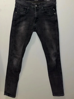 Replay Anbass svarta skinny jeans - Snygga Replay Anbass jeans i svart tvätt med diskreta slitningar och klassiska fem fickor. Skinny fit med smal passform och stretchigt jeanstyg för extra komfort. Bakfickorna har Replay-logga och dekorativa sömmar. Perfekta för dig som gillar en modern look. Riktigt schyssta.