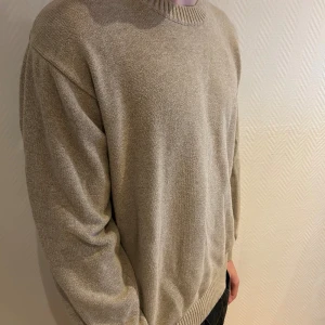 Beige stickad tröja från Bison - Hej 👋Säljer min snygga beige stickad tröja från Bison med rundad hals och ribbade muddar. Tröjan har en loose passform och är perfekt för dig som gillar en enkel och clean stil. Passar dig som vill ha något mjukt och bekvämt under hösten och vintern. Hör av dig vid frågor och funderingar✅💬