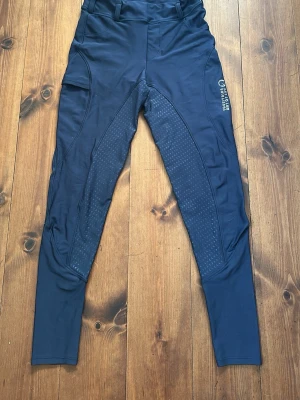 Marinblå ridbyxor - Marinblå fullskodda ridbyxor. Modellen är väldigt likt (nästan identiska) ett par från Maya Delorez. Ridbyxorna är i barnstorlek L men skulle säga att de passar vuxen XS.