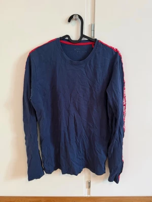 Blå långärmad t-shirt Alpha Industries - Säljer en mörkblå långärmad t-shirt från Alpha Industries med röda band längs ärmarna