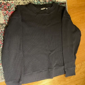 Mörkgrå tröja - Säljer en mörkgrå långärmad tröja från Cubus i storlek 146/152. Tröjan har en ribbad struktur och rund halsringning, perfekt för dig som gillar enkel och stilren design. Passar dig som vill ha en basic och bekväm tröja till garderoben.