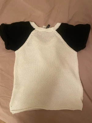 Vit och svart stickad tröja från H&M - Säljer en stickad tröja från H&M i storlek S. Tröjan har vit kropp och svarta korta ärmar, med rund halsringning. Perfekt för dig som gillar kontraster och enkel stil. Materialet är mjukt och luftigt stickat, passar bra till både jeans och kjol.