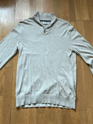 Beige half zip tröja Jack & Jones - Snygg beige långärmad tröja från Jack & Jones med half zip i halsen. Tröjan har ribbade muddar och är tillverkad i mjuk bomull, perfekt för chill dagar. Enkel och stilren design som funkar till jeans eller chinos. Hör av er om funderingar!