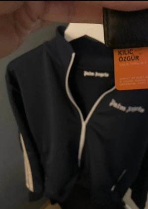 Mörkblå trackjacka från Palm Angels - Säljer en mörkblå trackjacka från Palm Angels med vita detaljer och dragkedja framtill. Storlek M