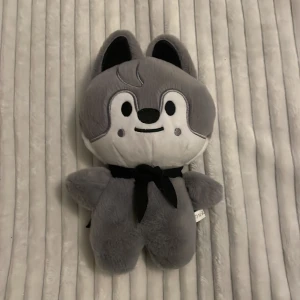 Skzoo Wolfchan  - Mjuk och söt varg-gosedjur med svart scarf och broderade detaljer. Passar perfekt som present eller dekoration. Observera att det finns ett mindre hål på baksidan, se bild 3. I övrigt gott skick och mycket mjuk.