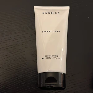 ESSNCE Sweet Cara Body Lotion 200ml - Body lotion från ESSNCE i doften Sweet Cara med inslag av kokos, pistage, jasmin och vanilj. Tuben är vit med svart lock och rymmer 200 ml. Tillverkad i Frankrike och vegansk, med mjukgörande ingredienser som sheasmör och solrosolja.