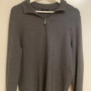 Grå quarter-zip från Massimo Dutti - Snygg grå tröja från Massimo Dutti med dragkedja och ribbad krage. Perfekt för kyligare dagar med sin stilrena design och bekväma passform. Storleken är M men sitter lite liten i storleken.