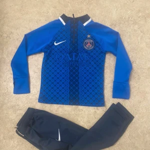 Blå PSG fotbollströja Nike långärmad - Säljer en blå långärmad PSG fotbollströja från Nike med geometriskt mönster på framsidan och Qatar Airways tryck. Tröjan har svart krage med vit detalj och PSG-logga på bröstet. Materialet är syntetiskt och passar perfekt för träning eller match.