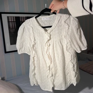 Vit blus från Zara - Jättesöt vit blus med lite volanger och broderi. Från Zara kids storlek 13-14, men den är som en XS. Säljer pga för liten. 