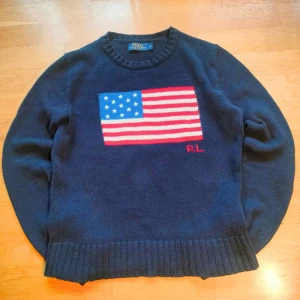 Polo Ralph Lauren USA Sweater 90s med USA-flagga🇺🇸 - Säljer en ikonisk Polo Ralph Lauren stickad tröja med den klassiska USA-flaggan framtill. Storlek S och i riktigt fint skick, nästan som ny! Nypriset ligger runt 5000 kr, mitt pris är 1199 kr och pris kan diskuteras vid snabb affär 🤝  Perfekt för dig som älskar old money / 90s heritage-stilen eller vill lyfta en enkel outfit med en äkta klassiker. Tjock, mjuk och kvalitén är vad man förväntar sig av Polo – håller i många år till.  📦 Skickar snabbt 🙂 Fråga gärna om mått eller fler bilder 🧼 Fräsch