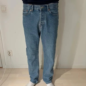 Jack & Jones ljusblå jeans straight fit - Klassiska Jack & Jones jeans i ljusblå tvätt med rak passform och hög midja. Jeansen har fem fickor, knappgylf och tydliga Jack & Jones -detaljer som nitar och läderpatch bak. Perfekta för dig som gillar tidlös denimstil.