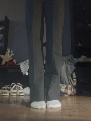 Gråa kostymbyxor med pressveck - Snygga gråa kostymbyxor med hög midja och raka ben. Byxorna har tydliga pressveck framtill som ger en clean och stilren look. Materialet är slätt och känns bekvämt mot huden. Perfekta för dig som gillar minimalistisk och klassisk stil.