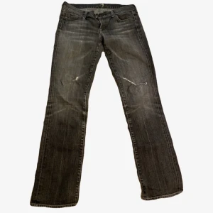 Svarta bootcut jeans från 7 For All Mankind - Snygga svarta jeans från 7 For All Mankind i bootcut-modell. Jeansen har slitna detaljer och en tvättad look, klassiska fem fickor och dragkedja. Perfekta för dig som gillar en avslappnad men trendig stil.