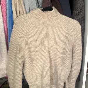 Beige stickad tröja Weekday XS - Säljer en beige stickad tröja från Weekday i storlek XS. Tröjan har ett ribbat mönster och hög hals som ger en chill vibe. Perfekt för lager-på-lager och har långärmade ärmar. Snyggt strukturerad och passar dig som gillar neutrala färger.