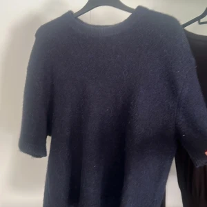 Mörkblå stickad tröja Gina Tricot - Mysig mörkblå stickad tröja från Gina Tricot i storlek S. Tröjan har korta ärmar och rund halsringning, perfekt för lager-på-lager. Materialet är fluffigt och ger en skön känsla. Enkel och stilren design som funkar till jeans eller kjol.