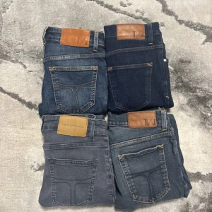 Tiger of Sweden Jeans  - Fyra par  jeans från Tiger of Sweden i olika tvättar: grå, mörkblå och två olika blå nyanser. Klassisk femficksmodell med läderpatch bak i midjan och smal passform hela vägen ner. Perfekta för dig som gillar stilrena och slim jeans.