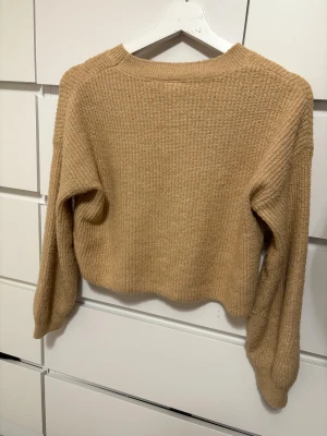Ljus brun stickad tröja från Lindex - En ljus brun tröja från Lindex som är väl använd och därför en aning nopprig. Tröjan är i storlek barnstorleken 146/152 men passar ändå någon som har ungefär xs och vill ha en croppad look.