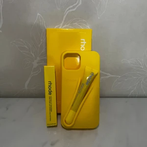 Rhode Lip Case & Peptide Lip Tint Lemontini Ballerini - Snyggt gult Rhode Lip Case med tillhörande Peptide Lip Tint i färgen Lemontini Ballerini. Perfekt för att förvara och applicera läpprodukten på språng. Produkten är ny och oanvänd, levereras i originalförpackning. Inga synliga defekter eller slitage. iPhone 13