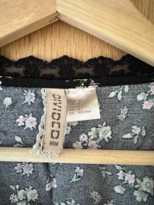 Blommig omlott spetstopp - Blommig v-ringad omlott topp med spets. Matchande shorts säljs i separat annons. Storlek XS-S. Svart, rosa, grön.