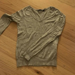 Grå v-ringad tröja från 157 - Grå v-ringad tröja från 157 i storlek XS. Tröjan har långärmade ärmar och ribbade muddar vid ärmslut och nederkant. Enkel och stilren design som funkar till många olika looks. Perfekt för dig som gillar basic och bekvämt.