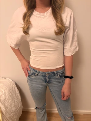 Vit croppad topp med rosett  - Vit topp med roset från lager 157. Helt ny och prislappen är fortfarande kvar, inte använd förutom för foto. 💕säljer för orginalpris. Modellen är ungefär 158 cm och bär storlek S. Väldigt bra passform för storleken.