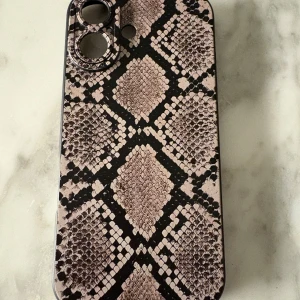 iPhone 16 skal ormmönster - Stilrent mobilskal med ormmönster, passar iPhone 16. Oanvänd, ger bra skydd och har exakta utskärningar för kamera, knappar och portar. Perfekt för dig som vill kombinera stil med funktion.