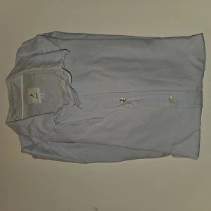 Ljusblå skjorta från boomerang - Snygg ljusblå skjorta klassisk krage och pärlemorknappar framtill. Skjortan är tillverkad i mjuk bomull och har en stilren look som passar perfekt till jeans eller chinos.