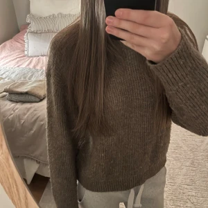 Brun stickad tröja från H&M - Mysig brun stickad tröja från H&M i storlek S. Tröjan har rund hals, ribbade muddar och långärmad passform. Perfekt för att hålla värmen under kyliga dagar och har en klassisk, enkel look som är lätt att matcha med jeans eller kjol.