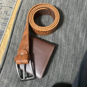 Brunt skinnbälte med struktur - Säljer ett snyggt brunt bälte i skinn med tydlig struktur och silverfärgat spänne. Bältet har en klassisk form och passar perfekt till jeans eller chinos. Den naturliga bruna färgen och det robusta materialet ger en cool och tidlös vibe.